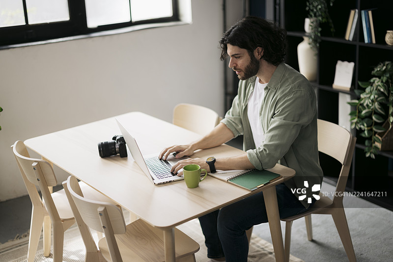 年轻男子在家办公，使用笔记本电脑图片素材