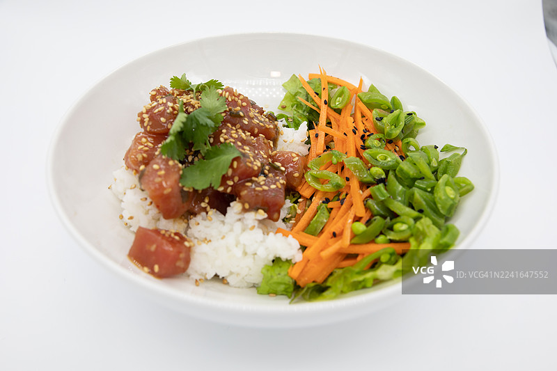 特写镜头，一个美味的夏威夷盖浇饭，上面有新鲜的金枪鱼、米饭和蔬菜，背景为白色。图片素材