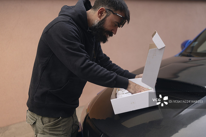 年轻的摩托头汽车爱好者在户外检查汽车零件图片素材