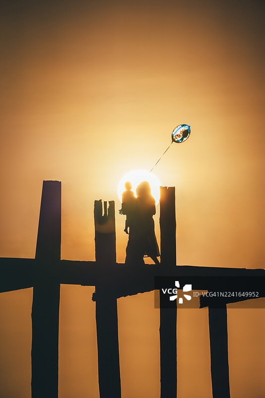 缅甸曼德勒阿玛拉普拉乌本桥上的成人与儿童剪影，日落时分图片素材