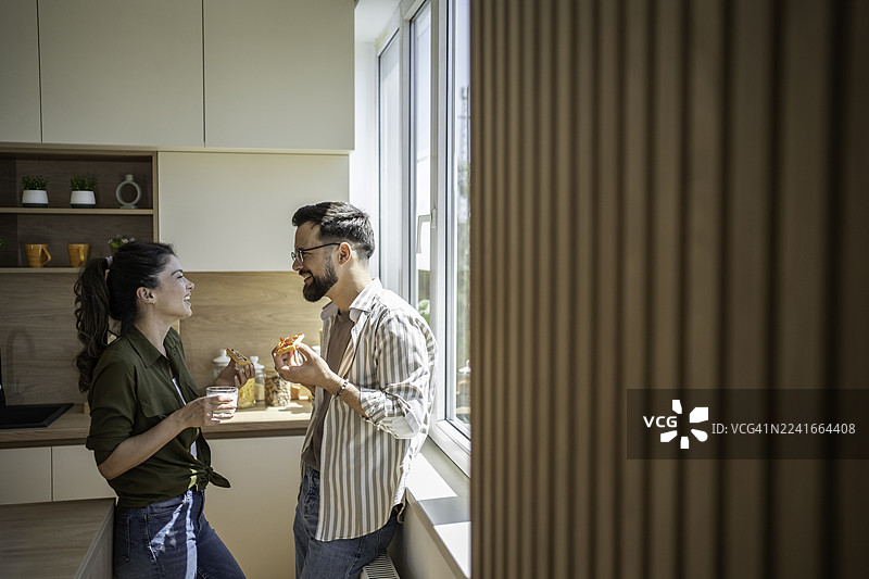 情侣在厨房里笑着吃披萨图片素材