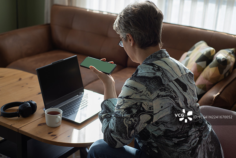 戴眼镜的女士在家用笔记本电脑购物，面带微笑图片素材