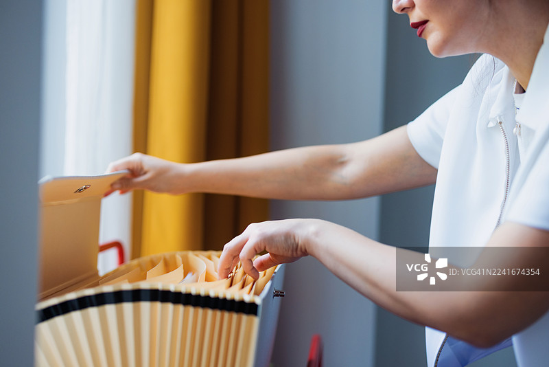 办公室邮件分拣：一人将信封放入扇形折叠邮件托盘图片素材