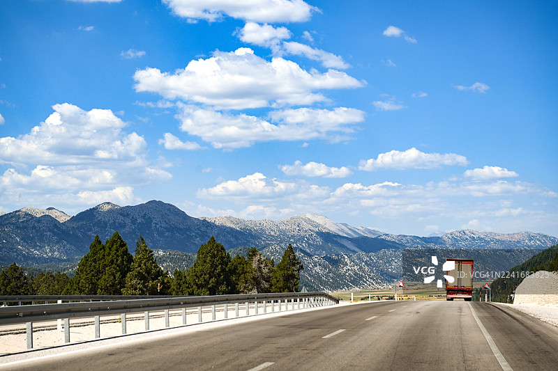 一辆载有干货半挂车的货物卡车沿着山脉在高速公路上行驶图片素材