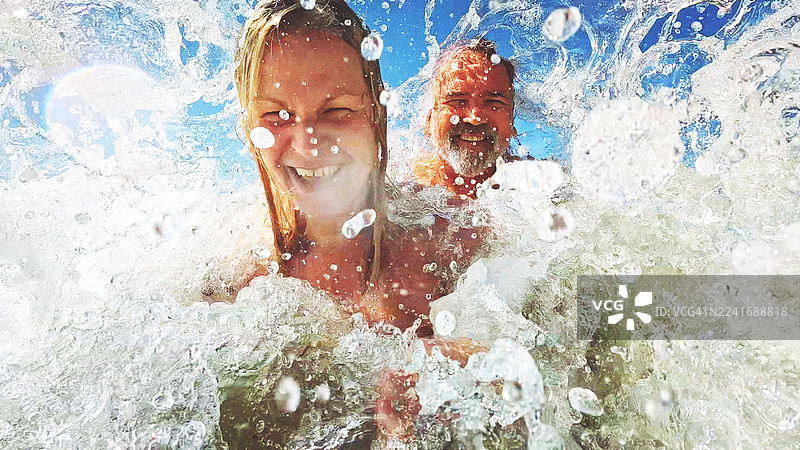 一对有趣的夫妇在波涛汹涌的波罗的海海浪中拍摄自己图片素材