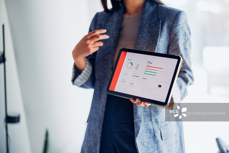 女商人正在现代办公室环境中用数字平板电脑展示数据图片素材