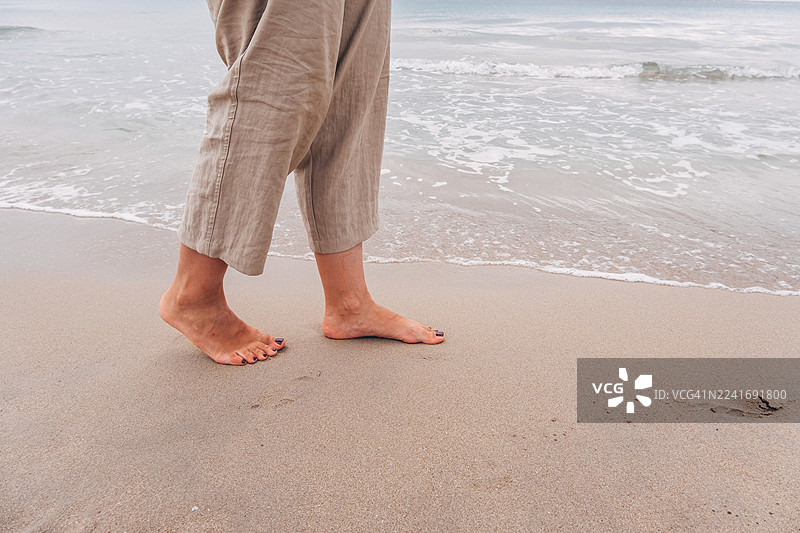 女子赤脚在沙滩上行走，海浪，度假休闲图片素材