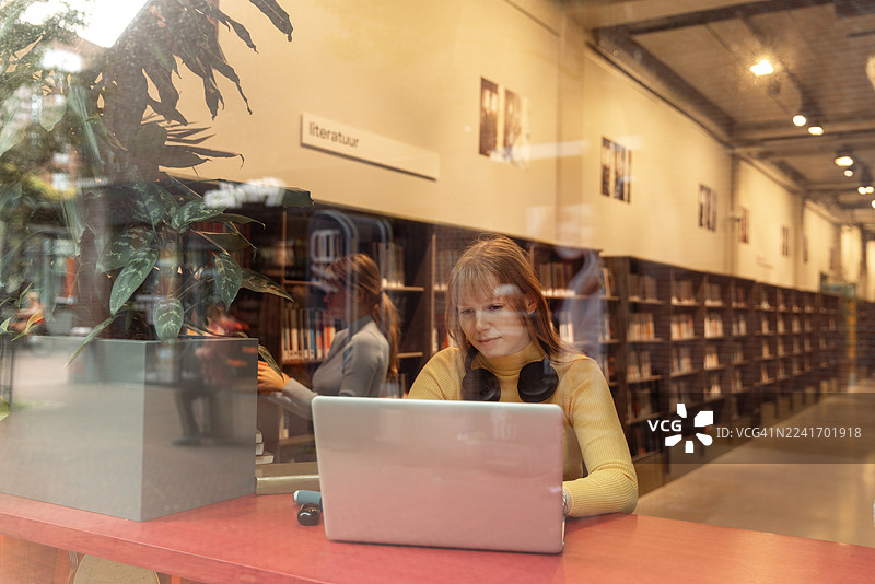 一位美丽的金色头发的十几岁女学生在图书馆学习图片素材