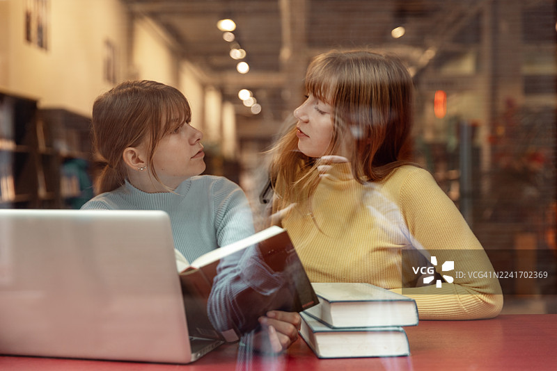 两位十几岁的姐妹在图书馆一起学习图片素材