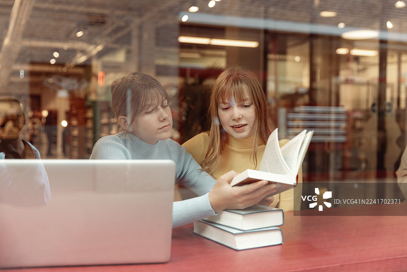 两个十几岁的姐妹在图书馆一起学习图片素材