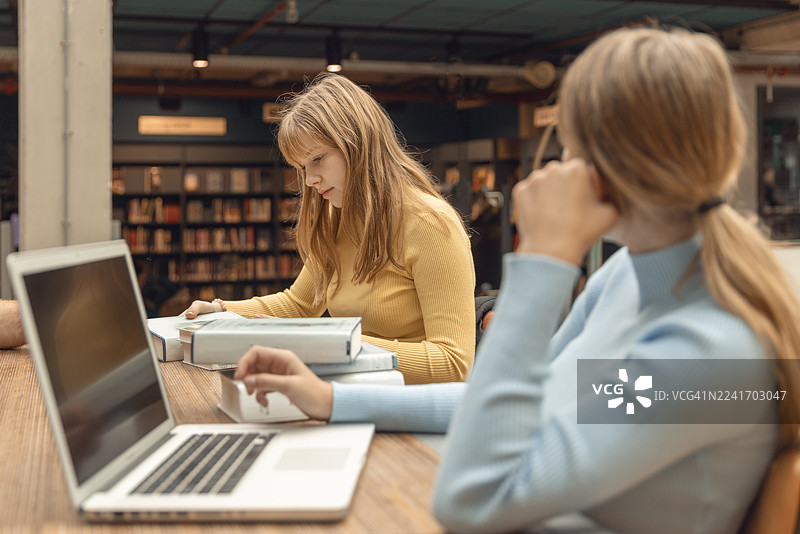 两个十几岁的姐妹一起在图书馆学习图片素材