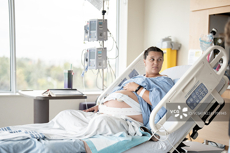 现代产房中，孕妇在分娩期间躺在病床上，身上连接着监护仪。图片素材