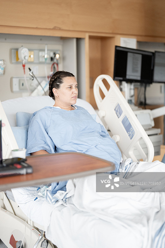 孕妇在分娩期间在医院病床上休息，旁边有医疗设备图片素材