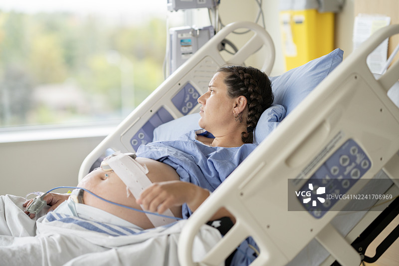 孕妇在分娩期间躺在医院病床上休息，并配有监护设备图片素材