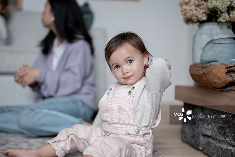 客厅地板上，一家人与幼儿共享温馨亲密的时光，柔和的光线营造出宁静的氛围图片素材