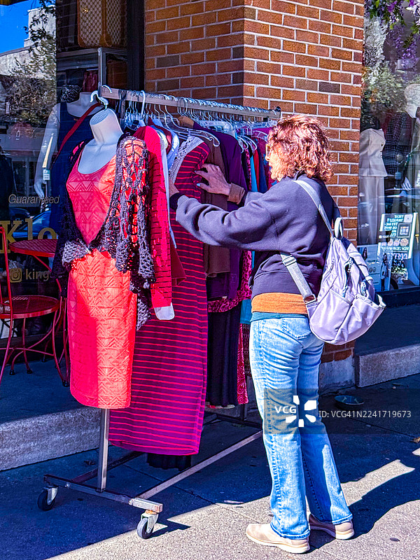 女人在萨拉托加泉的街道边衣架上挑选衣服图片素材
