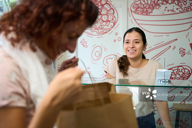 顾客取走打包好的餐点，店员面带微笑图片素材