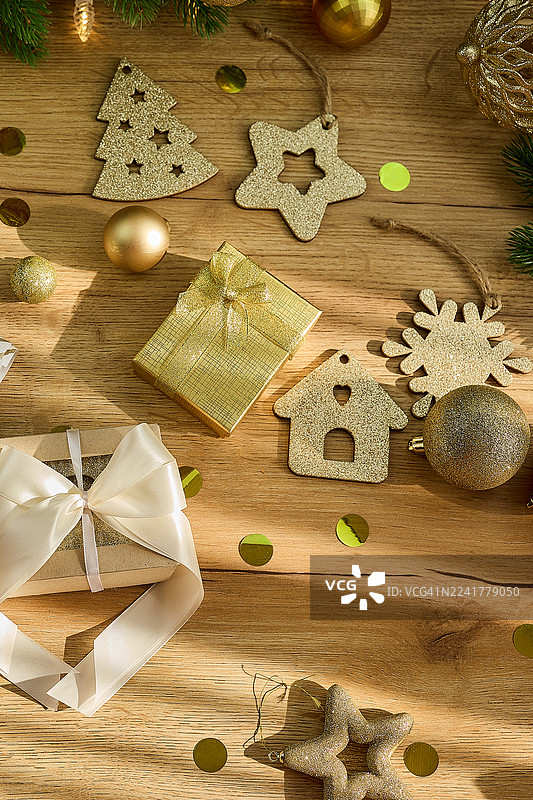 金色的圣诞礼物，上面有包装好的礼品、装饰品和纸屑，摆放在木桌上图片素材