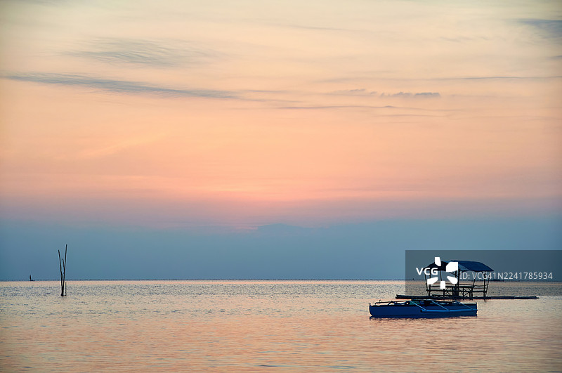 宁静的日落将温暖的橙色和柔和的蓝色投射到天空中。图片素材