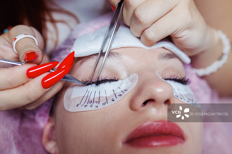 美容院里使用精密工具进行睫毛嫁接的特写图片素材