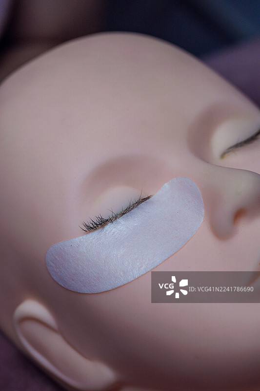 特写：一位模特的眼睛在嫁接睫毛治疗期间贴有眼下贴片图片素材