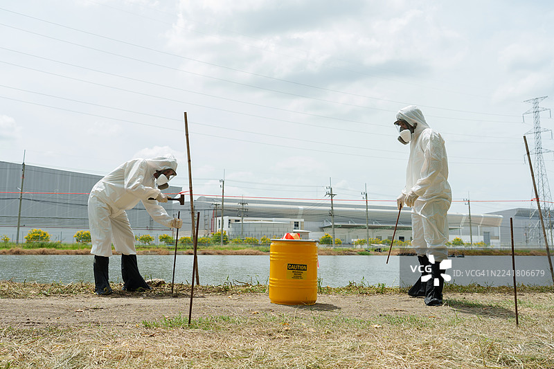 生态学家身着防护服，在养殖水生动物的农场池塘中检查水质，并采集水样进行分析。图片素材