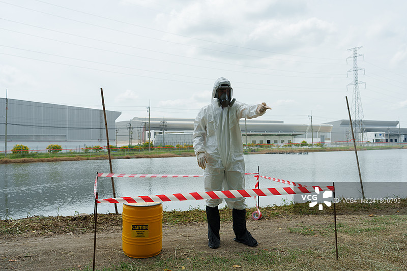 生态学家身穿防护装备，在养殖水生动物的农场池塘中检查水质，并采集水样进行分析。图片素材