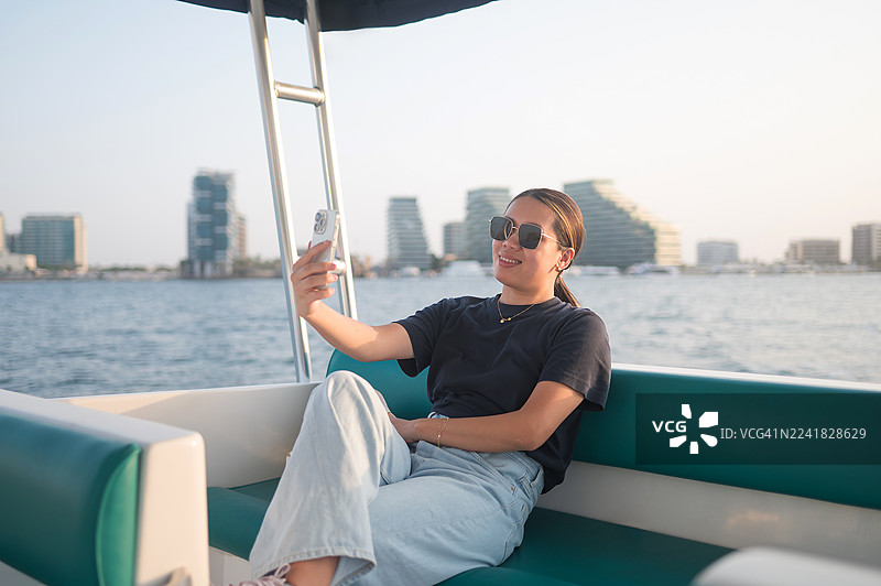 女子在船上享受悠闲时光，手持手机放松图片素材