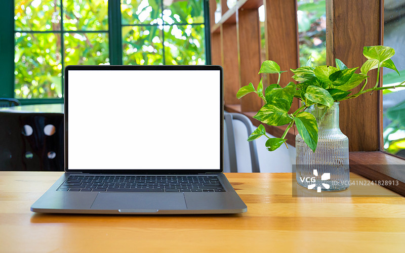 咖啡馆背景下的笔记本电脑，屏幕空白，摆放在桌上。笔记本电脑屏幕带有复制空间。舒适的工作场所。正面视图。网上冲浪。视频会议。在线购物。图片素材