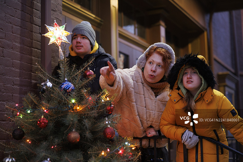 红发妈妈带着患有自闭症的儿子和女儿在历史悠久的波科诺小镇度假观光。晚上，在宾夕法尼亚州吉姆·索普镇，他们走过装饰好的圣诞树。图片素材