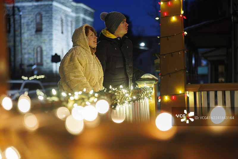 一位红发母亲和患有自闭症的青少年在宾夕法尼亚州吉姆·索普欣赏节日灯光，背景是历史悠久的石头建筑。图片素材