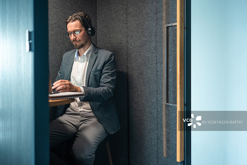 一位坚定的中年白人商人正在现代办公室隔间里工作图片素材