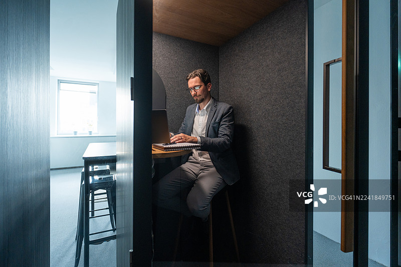 专注的中年专业人士在现代办公室隔间工作图片素材