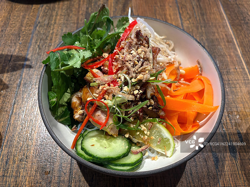 越南鸡肉沙拉，配有香茅烤鸡、黄瓜、胡萝卜、米粉、辣椒、香菜、薄荷、脆炸葱头、花生和鱼露酱图片素材