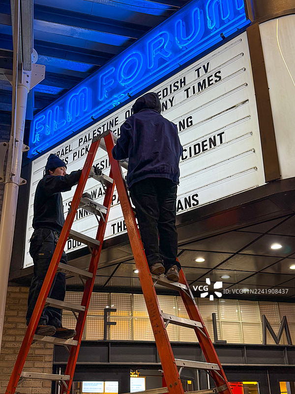 人们在纽约电影论坛的招牌上爬梯子更换电影片名图片素材