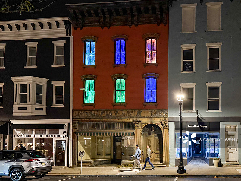 纽约哈德逊沃伦街建筑的霓虹彩色窗户下夜晚行走的人们图片素材