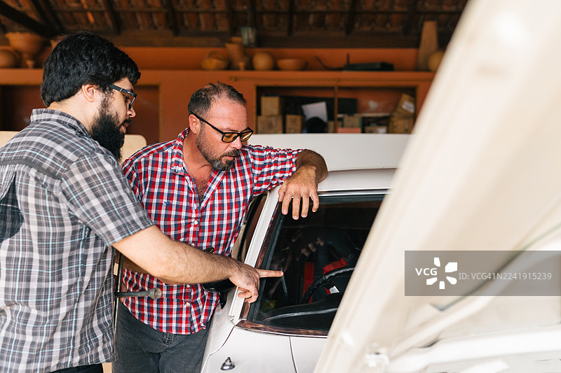 朋友们在讨论经典肌肉车修复的细节图片素材