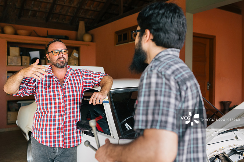 两名男子在车库里讨论经典肌肉车图片素材