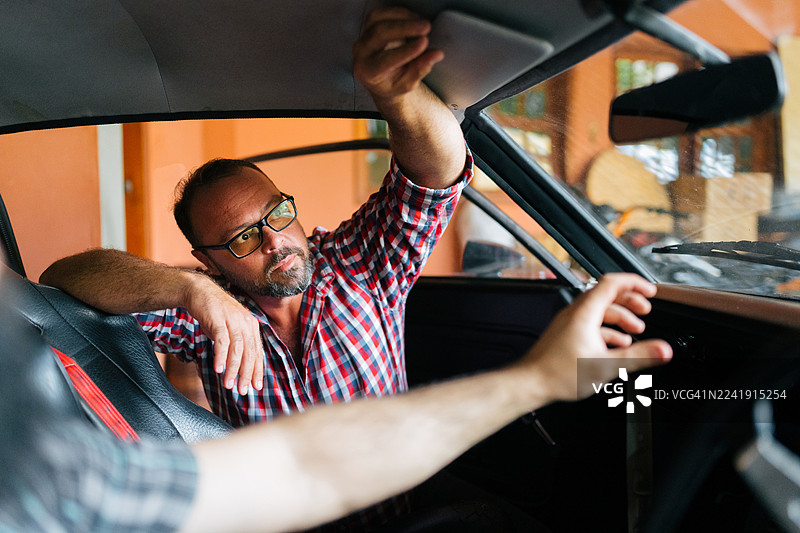 男人正在调整经典汽车的内顶衬图片素材