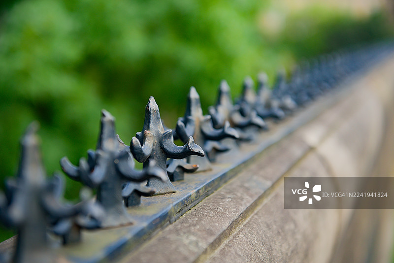 老式铁栅栏顶部的装饰性防盗墙尖刺图片素材