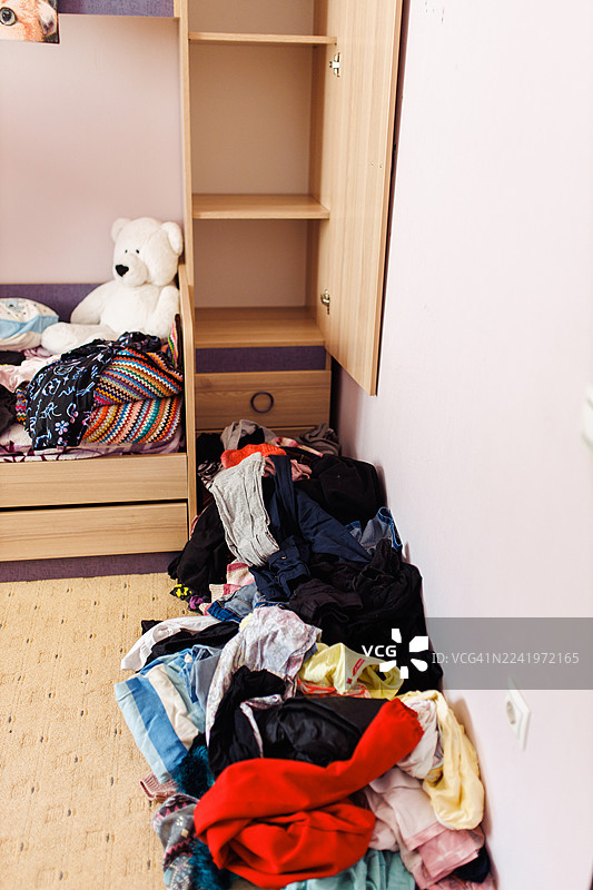 凌乱的青少年房间，衣柜敞开，衣服散落一地，床上放着一只白色泰迪熊图片素材