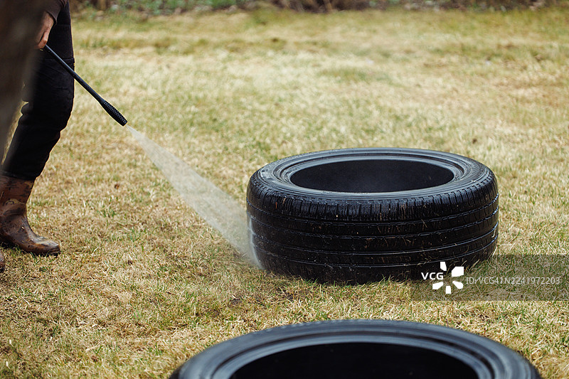 户外洗车轮轮胎保养：有人在户外用水喷洗轮胎图片素材