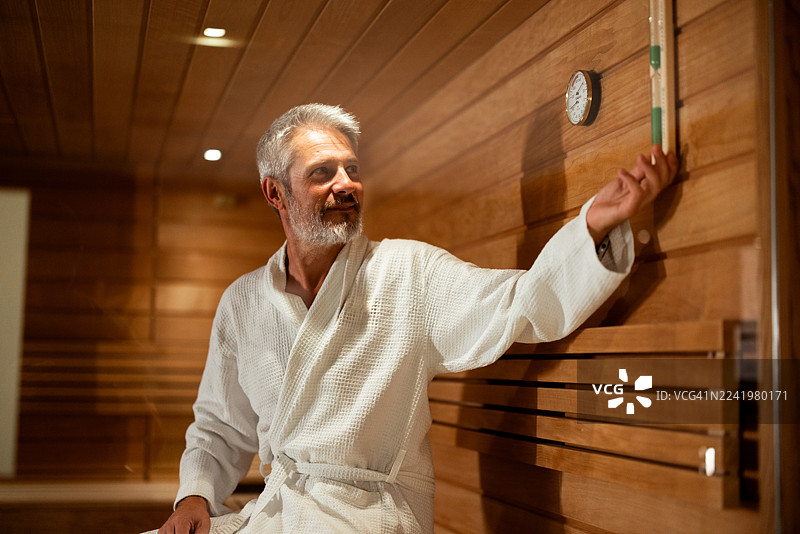 一位成熟的男士在桑拿房放松，查看温度计图片素材