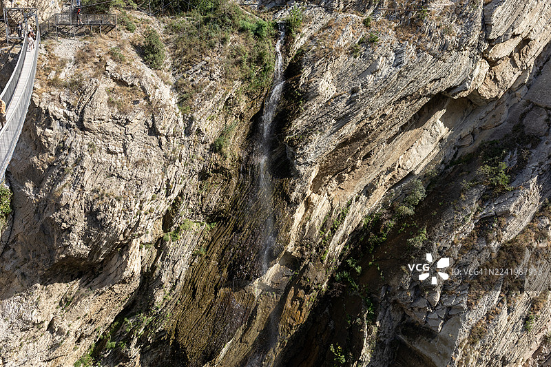 风景如画的山间峡谷，有瀑布和玻璃栈道，俯瞰崎岖的山崖，游客们正在享受自然和探险。图片素材