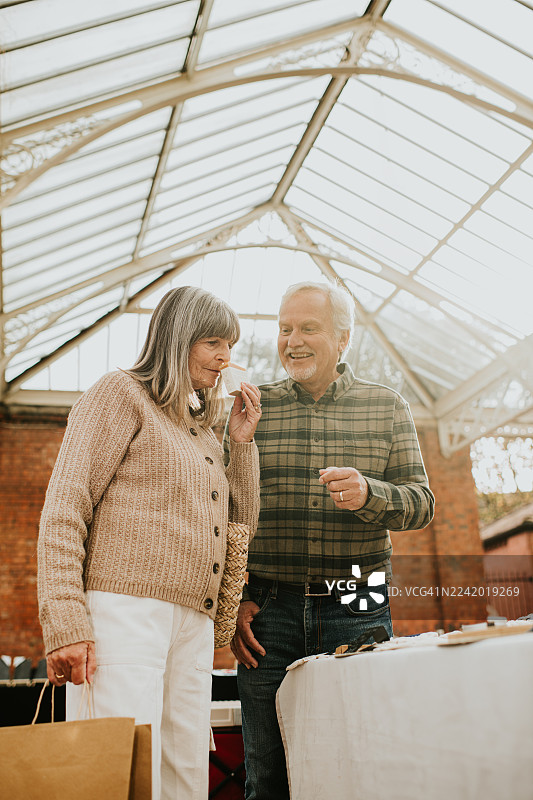 从低角度拍摄，一对成熟的夫妇正在市场摊位上挑选肥皂图片素材