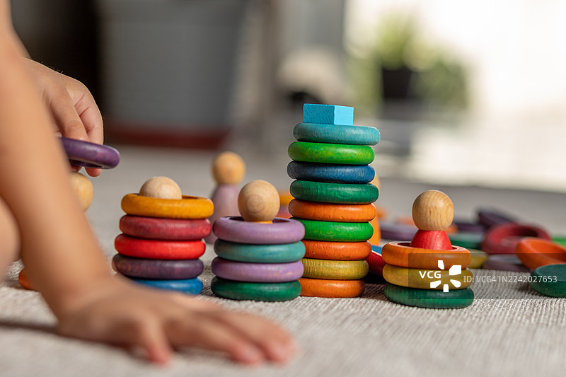 在阳光明媚的游乐室里，柔软的地毯上堆放着色彩鲜艳的套圈和玩具图片素材