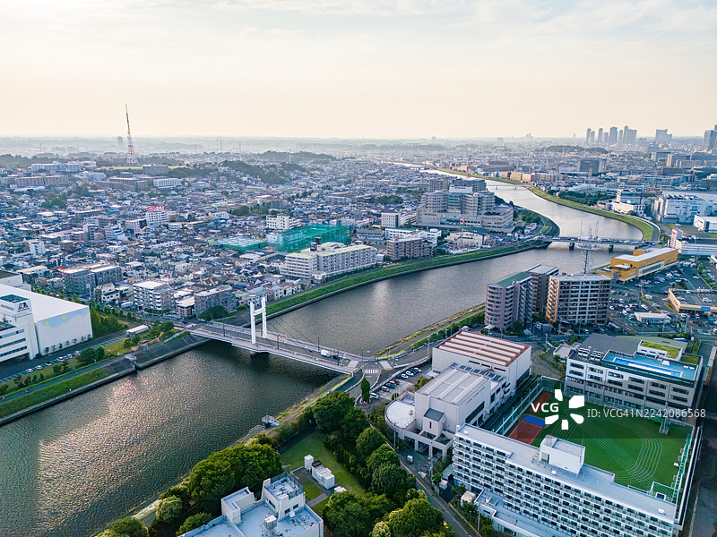 京急电铁的铁轨。净水厂。夕阳倒映在河面上。横跨河流的桥梁。鹤见川的无人机航拍。图片素材