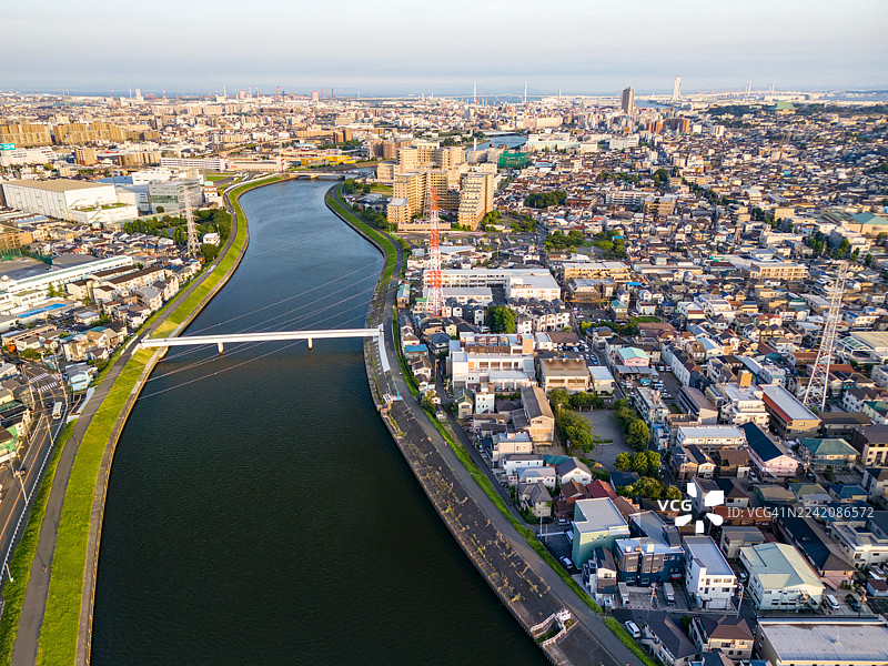 高压电线。日落倒映在河面上。河上的桥梁。鹤见川的无人机航拍。图片素材