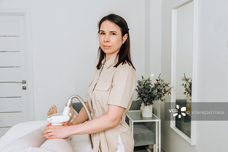 医生看着镜头，为女患者进行LPG按摩以减少皮下脂肪。图片素材