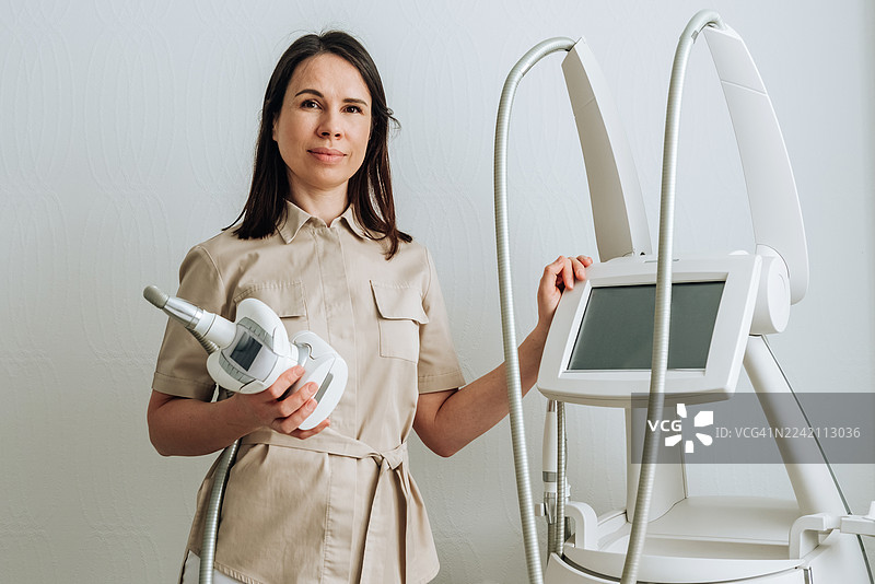 一位平静的女医生手持LPG按摩仪，正看向镜头图片素材